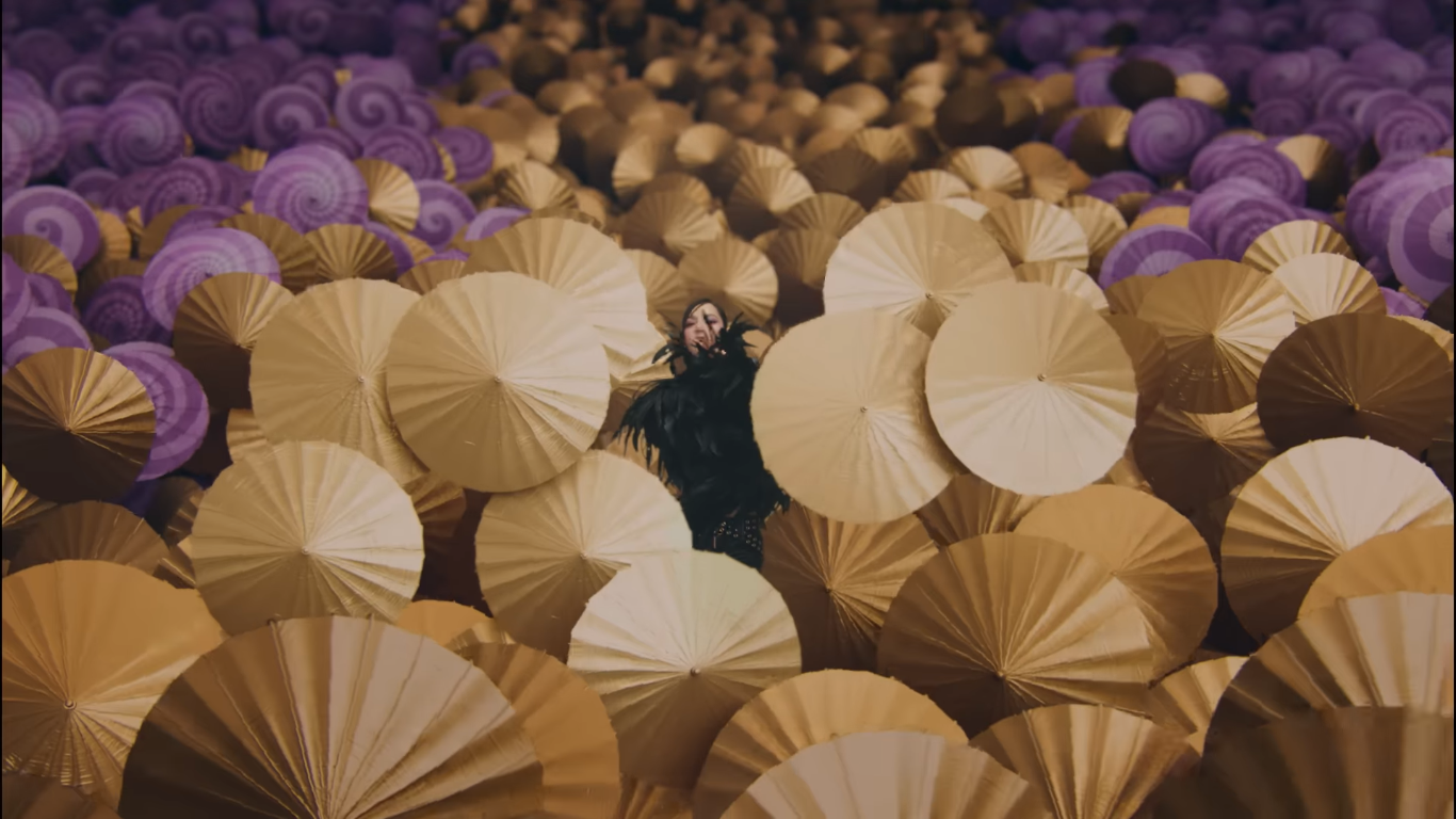 gaya kece lisa 'blackpink' dan  rosalía di music video 'new woman', 1. Lisa mengawali video musiknya dengan penampilan fierce. Memancarkan aura dark feminine, Ia pakai mantel hitam yang dikenakan di atas bra berkilauan dan celana pendek mikro yang serasi, dilengkapi dengan kalung hati metalik dan sepatu boots setinggi lutut., 2. Tampil dengan gaya a la gilded girl, Lisa pakai atasan metalik dan rok mini warna gold yang serasi. Suede boots warna nude dari Maison Margiela melengkapi gayanya., 3. Rosalía dengan gaya khasnya berikan sentuhan modern pada outfit yang terinspirasi dari flamenco. Ia mengenakan dress merah dengan potongan asimetris dengan garis leher rendah dipadukan dengan ankle boots merah. Warna merah yang berani menciptakan siluet dramatis yang kuat dan feminin., 4. Gaya Rosalía selanjutnya pakai bodysuit warna putih dengan motif floral merah dipadukan dengan heels hitam yang memancarkan nuansa vintage., 5. Dalam salah satu adegan, Lisa tampil fierce mengenakan pakaian bulu-bulu hitam, yang dipadukan dengan riasan mata gelap dan tatanan rambut sleek. , 6. Lisa bergaya edgy dengan atasan korset, celana kargo low-rise dan belt putih bergaya Y2K. Di adegan lainnya Ia melengkapi penampilannya dengan mantel bulu yang terinspirasi dari gaya Mob Wife yang vintage sekaligus berani., 7. Seperti Yin&amp;Yang, Lisa dan Rosalía mengenakan outfit hitam putih dengan dress berbahan sheer yang flowy., 8. Dalam adegan terakhir, Rosalía pakai mantel bertekstur warna pink yang dipadukan dengan kacamata biru reflektifnya yang memberi sentuhan modern. Di sampingnya, Lisa tampil kontras dengan outfit yang lebih edgy, mengenakan jaket kulit hitam dan putih dengan kacamata bergaya futuristik.