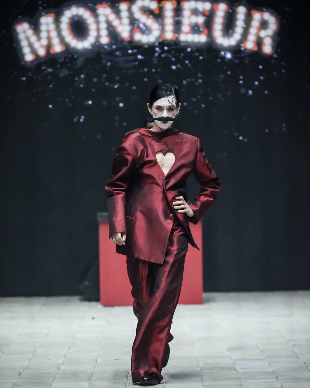 danjyo hiyoji hadirkan esensi kabaret yang semarak di pimfw 2024, 1. Koleksi ‘Monsieur’ dibuka dengan deretan look yang menampilkan setelan blazer yang pas dan celana panjang yang bervolume. Aksesori scarf dengan konstruksi kaku yang seolah tertiup angin memberi dimensi ekstra yang unik di sejumlah look., 2. Koleksi ini menangkap sensasi dari pertunjukan kabaret dengan menata ulang siluet busana pria klasik dengan volume yang berlebihan dan lapisan yang didekonstruksi., 3. Potongan asimetris dan kain berlapis menciptakan kontras visual yang mencolok. Elemen-elemen yang ceria seperti lengan yang besar dan motif yang dramatis menambahkan sentuhan unik yang memberi kejutan dalam koleksi ini., 4. Dwi Sasono jadi salah satu muse yang berjalan di runway, memamerkan koleksi setelan jas dengan sentuhan elemen floral dan celana serba putih yang dipadukan dengan inner warna silver dan scarf yang dirancang dengan konstruksi kaku., 5. Adinia Wirasti muncul dengan penampilan yang ikonik seperti di film The Greatest Showman. Mengenakan setelan jas yang mencolok dengan siluet yang dramatis, mewujudkan daya tarik kabaret yang serba glamor.