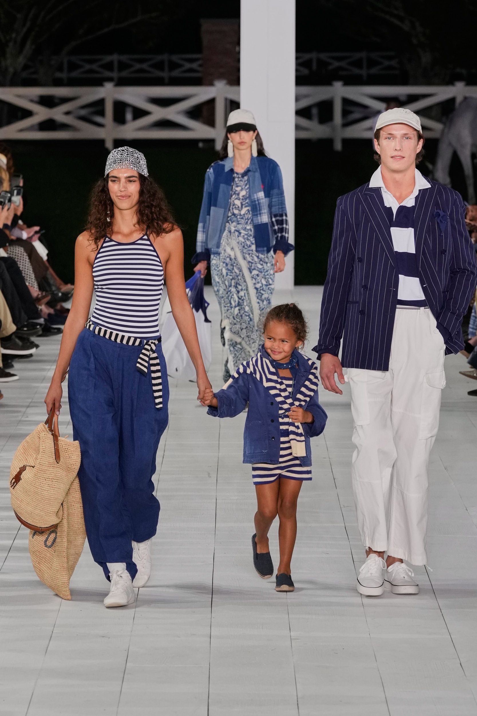 ralph lauren perlihatkan kehangatan keluarga di panggung s/s 2025, 1. Tren fashion “boho chic” beberapa kali terlihat di atas panggung runway Ralph Lauren Spring/Summer 2025. Meski tidak menerapkan motif bold, Ralph Lauren memanfaatkan satu set perhiasan batu permata serta belt berukuran lebar sebagai pelengkap look., 2. Mengutamakan sisi elegan seorang perempuan, koleksi terbaru gaun maxi milik Ralph Lauren didesain dengan sentuhan manis dari aksen taburan manik-manik, pola bunga-bunga, sampai tambahan cape untuk kesan dramatis saat hadiri acara formal., 3. Tidak hanya motif garis-garis, Ralph Lauren juga menyelipkan berbagai macam bentuk motif kotak-kotak yang disatukan dalam bentuk rok panjang bersiluet ekor putri duyung dengan konsep patched (tambalan)., 4. Salah satu fashion item unik dan (mungkin) jarang ditemukan dari koleksi terbaru Ralph Lauren adalah outer blazer warna warm tan yang didesain mirip seperti anyaman tanpa memiliki ornamen tambahan lainnya., 5. Dari awal hingga menjelang penutupan, model perempuan Ralph Lauren terus memperlihatkan berbagai macam model anting chandelier yang didominasi warna perak, navy dan putih., 6. Pada pertengahan show, Ralph Lauren mulai memperlihatkan suasana ceria khas musim panas lewat konsep pakaian color block (tabrak warna) yang mengkombinasikan palet warna terang, seperti kuning mustard dan biru gelap serta hijau dan orange., 7. Usung tema keluarga cemara, tidak heran jika peragaan busana Ralph Lauren Spring/Summer 2024 menghadirkan beberapa model cilik yang ikut berpartisipasi di atas runway bersama model dewasa dengan mengenakan setelan pakaian senada., 8. Masuk dalam jajaran koleksi tas terbaru Ralph Lauren, berbagai siluet tas tangan bermaterial kulit dengan top handle kayu serta aksen buckle yang timeless ternyata mengadaptasi dari kesukaan sang desainer terhadap mobil-mobil jadul.